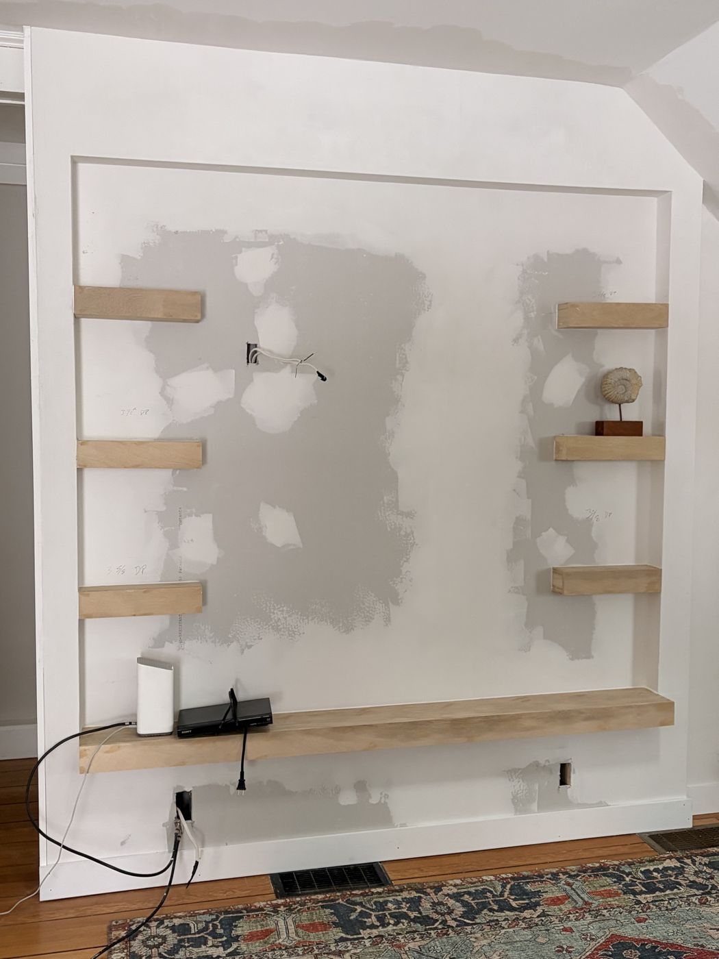 Floating shelves installed, wall skim-coated and awaiting paint