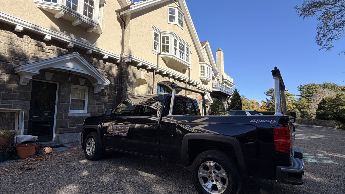 Black Big Dream Corp truck with company logo and phone number parked in front of a large stone-and-stucco house at a project site